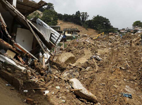 Landslide damages houses, debris covers hillside.