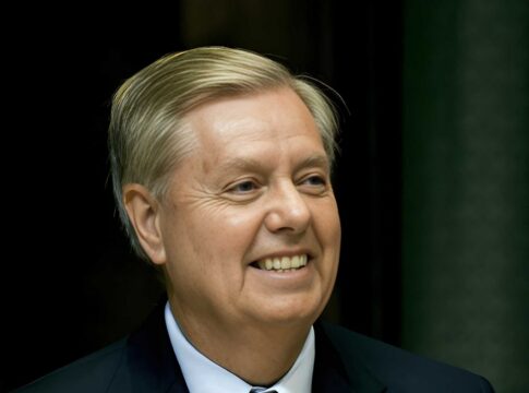 Smiling middle-aged man in a suit speaking at a podium