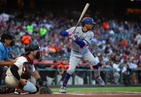 A baseball player from the Dodgers prepares to bat while the catcher is in position