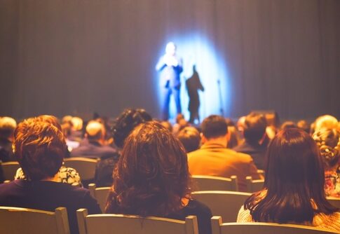 Audience watching a performance on stage with dramatic lighting