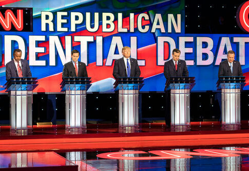 Republican presidential candidates debating on stage, CNN background.