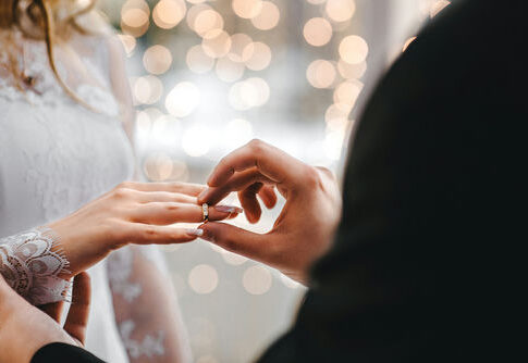 Groom placing ring on brides finger at wedding.